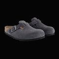 Pair of gray suede clogs with a buckle on a light gray background